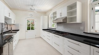 Galley kitchen with black stone worktops and grey metro tiles at Crystal Springs, St. James, Barbados