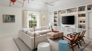 Family sitting room with library shelves, a corner sofa and caned armchairs at Crystal Springs villa, Barbados