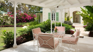 Covered verandah at Crystal Springs villa, set with coral-striped chairs beside bougainvillea beds, Barbados