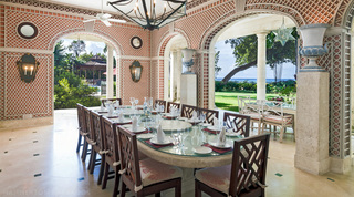 Four Winds covered terrace in Barbados, a dining table set for twelve amid lattice-patterned rendered walls