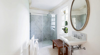 Marble walk-in shower with a round framed mirror and console basin, Four Winds villa in Barbados