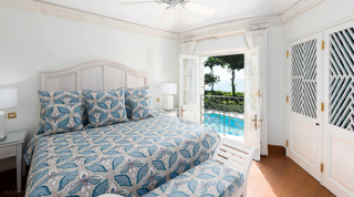 Blue floral bedroom with fretwork wardrobes, French doors open over the pool and sea at Four Winds, west coast Barbados