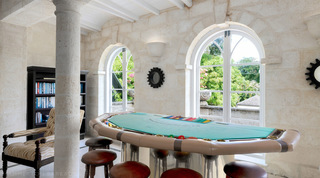 Blackjack table and leather-topped stools in the coral-stone games room at Four Winds, a villa rental in Barbados