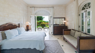 Four Winds bedroom with coral-stone walls, a cane-sided daybed and French doors opening to a garden terrace in Barbados