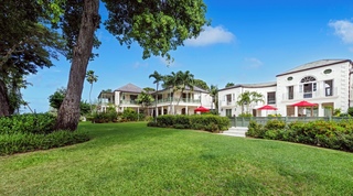 Wide garden lawn and rear elevation framed by mature trees at Four Winds in St. Peter, Barbados