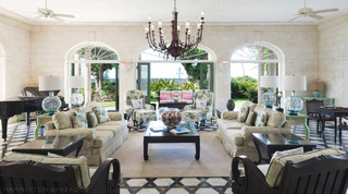 Living room with floral sofas, iron chandelier and arched garden windows at Four Winds luxury villa, Barbados