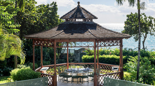 Wooden gazebo with a round dining table overlooking the water at Four Winds, Gibbs Beach, Barbados