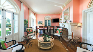 Coral-pink cocktail lounge with a five-stool bar and a shell-framed mirror at Four Winds, a Barbados villa rental