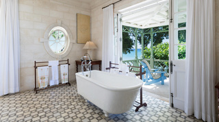 Bathroom with a freestanding tub, patterned tile floor and doors to a sea-facing terrace at Four Winds, Barbados