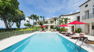Four Winds in Barbados, its rectangular pool ringed by red parasols and sun loungers below the villa wings