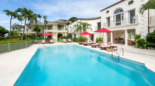 Four Winds poolside in Barbados, covered alfresco dining beneath arches with sun loungers along the deck
