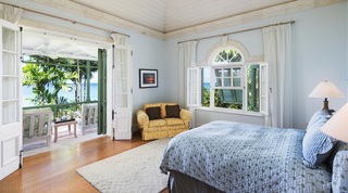 Blue bedroom with an arched window and terrace doors framing the Caribbean Sea at Four Winds, Barbados