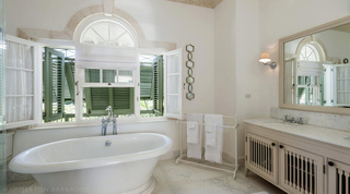 Four Winds bathroom in Barbados, a freestanding tub beside a marble-top vanity and arched shuttered window