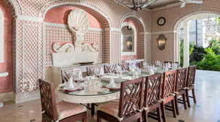 Carved stone scallop shell and dolphins behind the covered terrace dining table, Four Winds private villa in Barbados