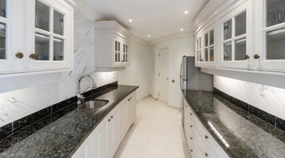 Galley pantry with white cabinets, dark granite counters and marble splashback at Four Winds, Barbados