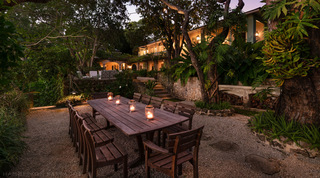 Lantern-lit timber dining table on the gravel terrace below the Great House, Fustic House in St. Lucy, Barbados