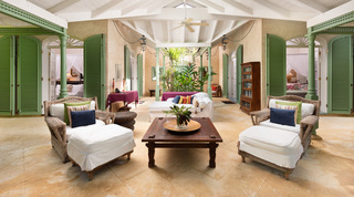 Plantation Wing sitting court at Fustic House, Barbados, with wicker armchairs and a rustic table between two suites