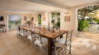 Fustic House dining room in Barbados, its long table beside an arched garden mural and open to the terrace