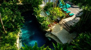 Lagoon-shaped rock pool seen from above beside the timber sun deck and green loungers at Fustic House in Barbados
