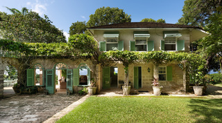 Two-storey wing of Fustic House with green shutters, zigzag-edged awnings and guardian lion statues by the lawn, Barbados