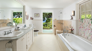 Marble-topped twin basins, a built-in bath and a doorway to a sea-view balcony at Fustic House, Barbados