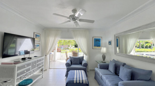 White ceiling fan and sheer curtains framing the terrace doors in Glitter Bay 107's living room, on Barbados' west coast