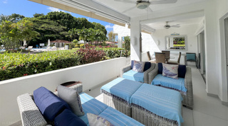Grey wicker terrace lounge with sky-blue throws under two ceiling fans, Glitter Bay 107 holiday apartment in Barbados