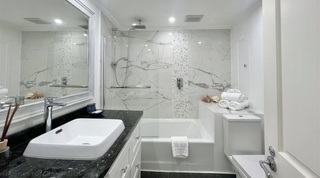 Bath with rain shower, penny mosaic strip and conch shells in a Glitter Bay 107 bathroom, holiday apartment in Barbados