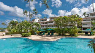 Tall coconut palms and green parasols around the communal pool at Glitter Bay 107, ground-floor apartment in Barbados