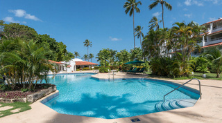 Curved steps into the communal pool with a terracotta-roofed pavilion beyond, Glitter Bay 107 in Porters, Barbados