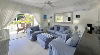 Soft blue sofa, armchairs and striped ottoman in the living room of Glitter Bay 107, open to the terrace, Barbados