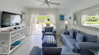 Flat-screen TV over a white wicker-drawer console facing the blue sofa at Glitter Bay 107, a Barbados apartment rental