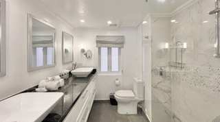 Twin vessel basins and a walk-in shower with white veined tiles in the Glitter Bay 107 apartment rental, Barbados