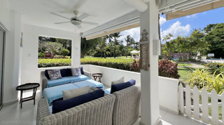 Open window in the terrace wall framing the garden beside a wicker sofa, Glitter Bay 107 luxury apartment, Barbados