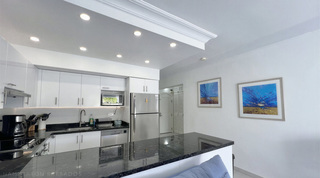 Two blue and gold abstract paintings beside the dark speckled breakfast bar in Glitter Bay 107's kitchen, Barbados