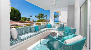 Covered terrace with striped banquette and sea views at Glitter Bay 204 Sea Men's Inn, St. James apartment in Barbados