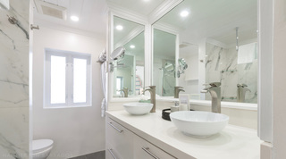 Twin vessel basins below framed mirrors and a marble wall, Glitter Bay 204 Sea Men's Inn holiday apartment in Barbados