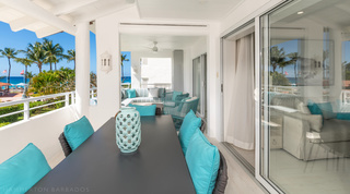 Terrace dining table set beneath the canopy with the Caribbean Sea beyond at Glitter Bay 204 Sea Men's Inn, Barbados