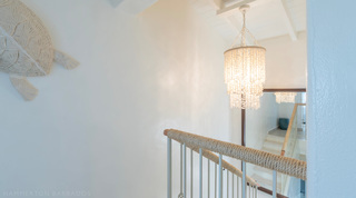 Landing with woven turtle wall art and beaded drum chandelier at Glitter Bay 301 – The Lighthouse, Barbados