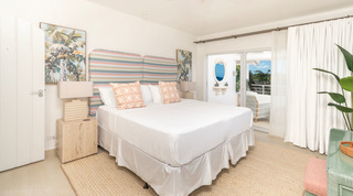 King bedroom with striped headboard and botanical art at Glitter Bay 301 – The Lighthouse, holiday apartment in Barbados