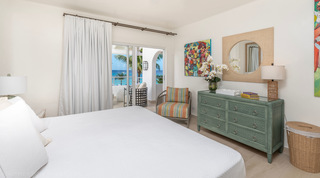 Glitter Bay 301 – The Lighthouse bedroom with green dresser and round mirror beside a terrace door, Barbados