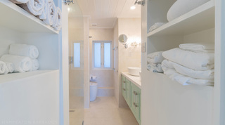 Glitter Bay 302 Bikini Bottom in Barbados, linen shelves stacked with towels beside the walk-in shower