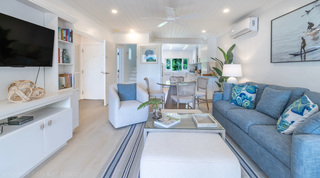 Open-plan living room with blue sofa opening to dining and kitchen at Glitter Bay 302 Bikini Bottom, Barbados