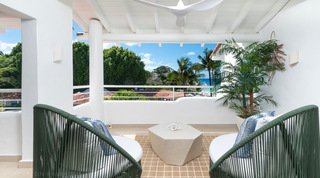 Covered balcony with green rope armchairs framing the sea at Glitter Bay 302 Bikini Bottom, luxury apartment in Barbados