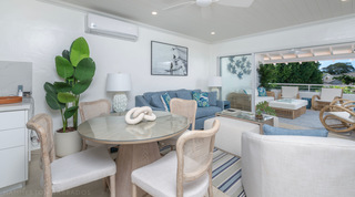 Round glass dining table set for four beside the lounge at Glitter Bay 302 Bikini Bottom, holiday apartment in Barbados