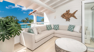 Terrace corner sofa below driftwood fish art with sea beyond, Glitter Bay 302 – Bikini Top apartment, Barbados