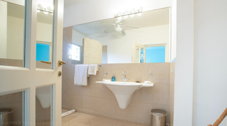 Bathroom with wall basin and a mirrored door at Jamoon villa, Barbados
