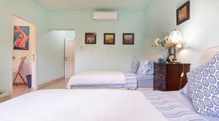 Green twin bedroom with framed art and an en-suite doorway at Jamoon villa, Barbados