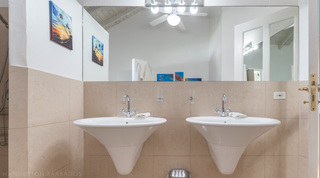 Bathroom with twin wall basins below beach-themed prints at Jamoon villa in Barbados