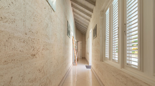 Coral-stone corridor with louvred shutters and a polished tile floor at Jamoon villa in Barbados